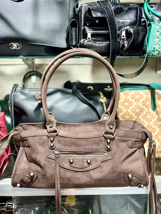Taupe suede city bag with antiqued studs, buckled straps and tasselled zip pulls